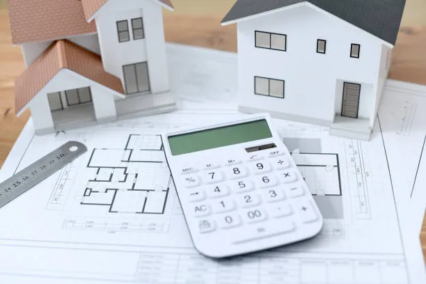 Architectural blueprints and a calculator, representing cost estimation.